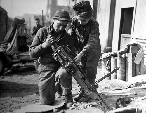 Photo:  A young French boy helps a machine gunner in Etzling, France